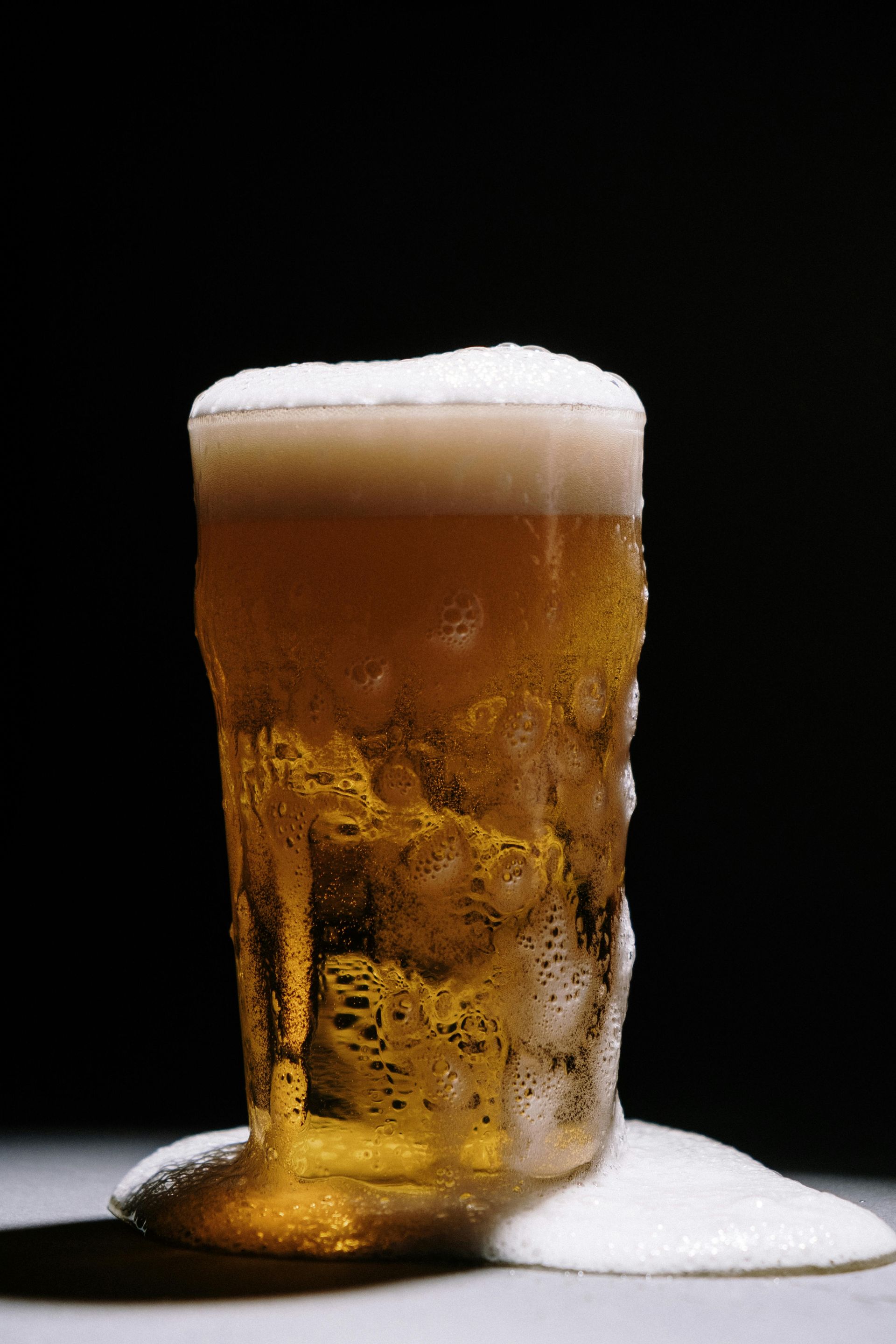 A glass of beer with foam coming out of it