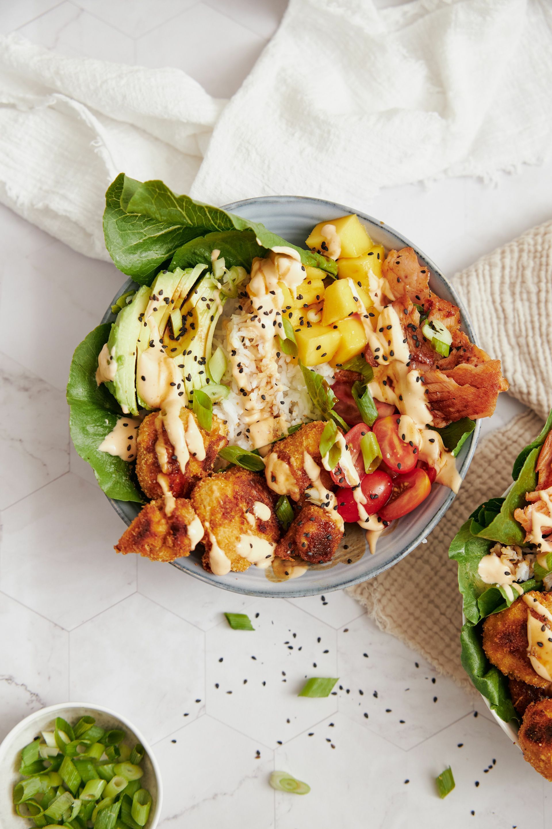 Bowl of lettuce wraps with chicken, avocado, rice, pineapple, tomatoes, and sauce.
