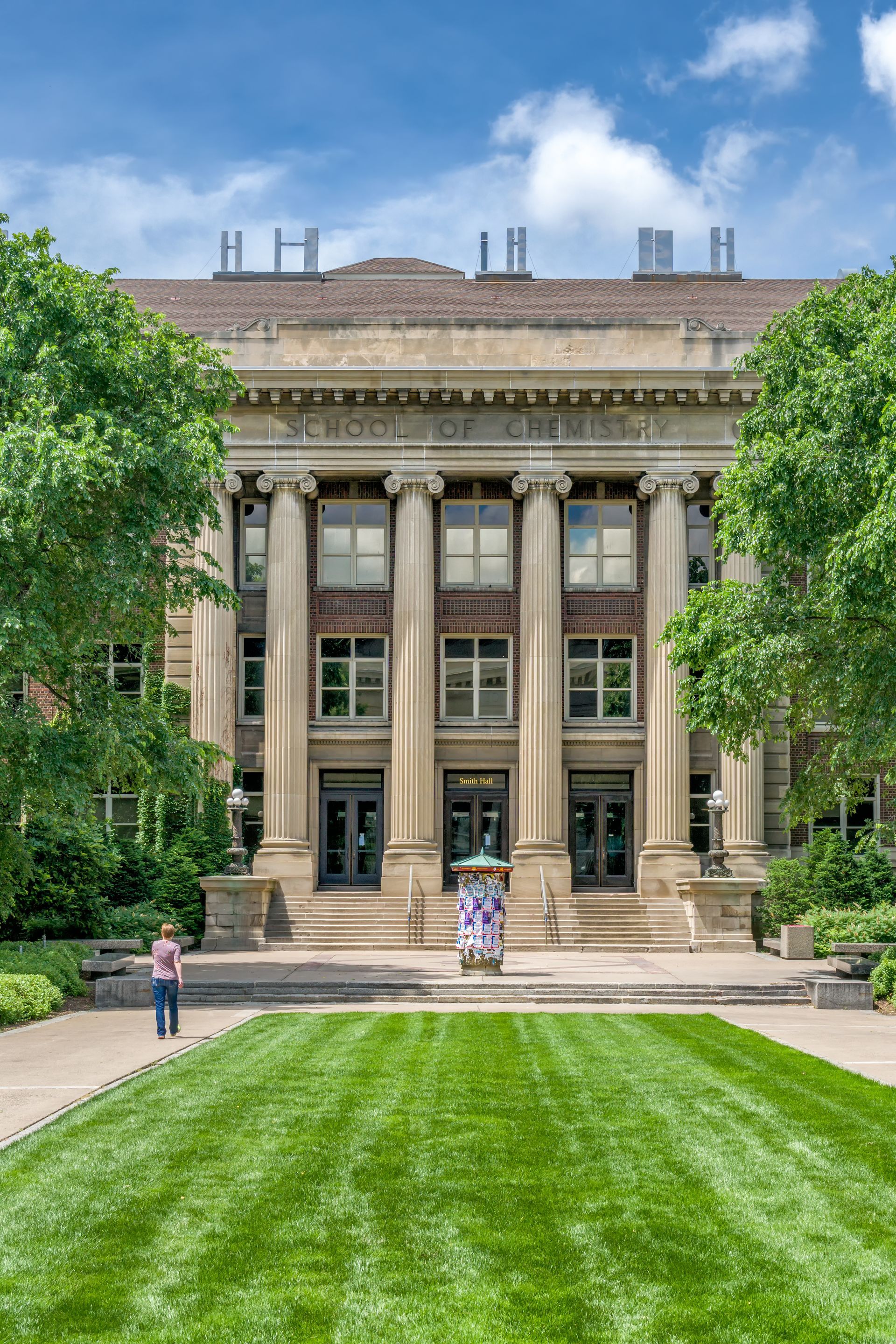 A large building with columns and a lush green lawn in front of it.