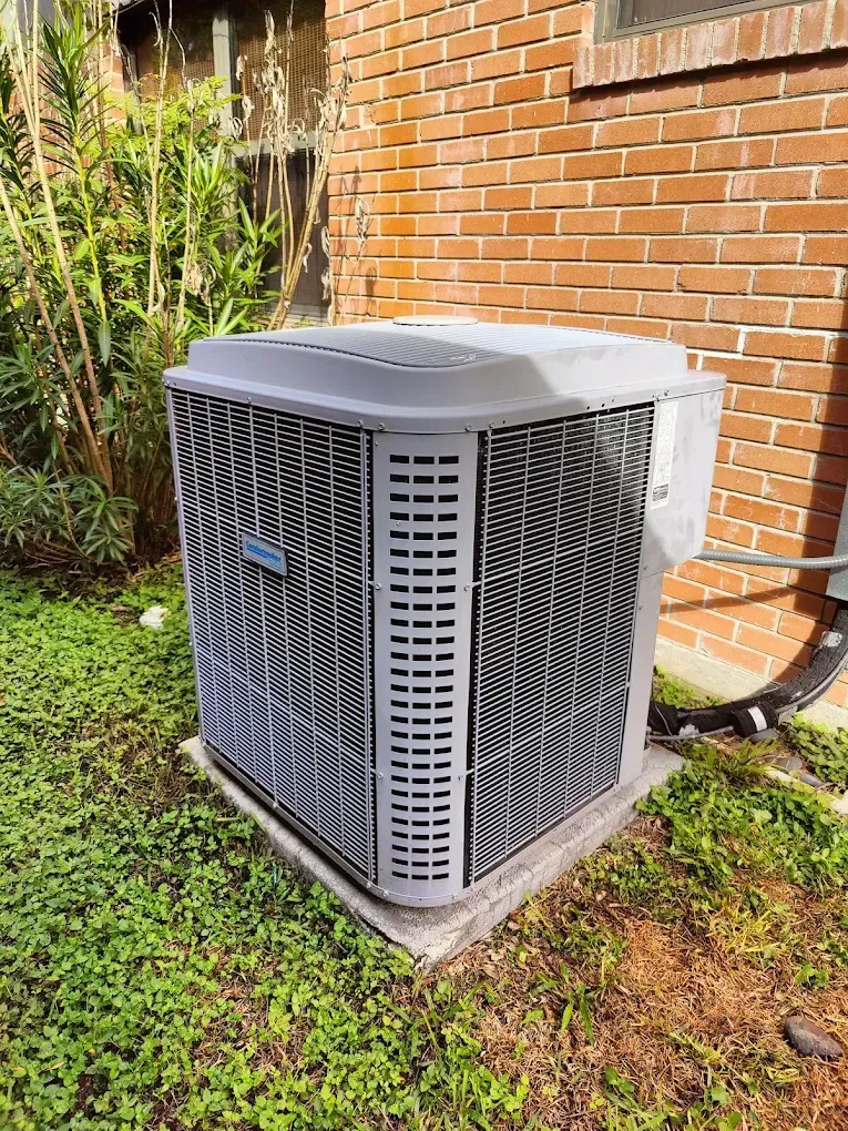 Gray air conditioning unit outside a brick building.