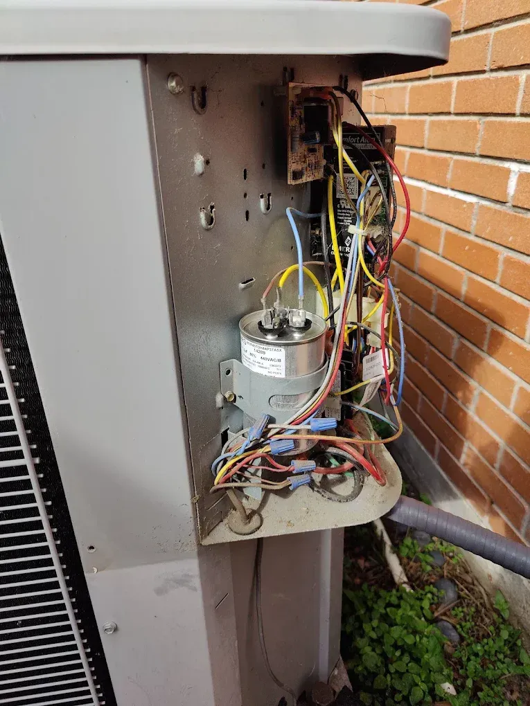 Open electrical panel on an AC unit; wires, capacitor, circuit board visible.