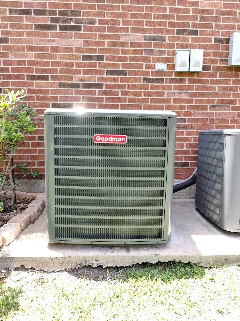 Goodman air conditioner unit against a brick wall.