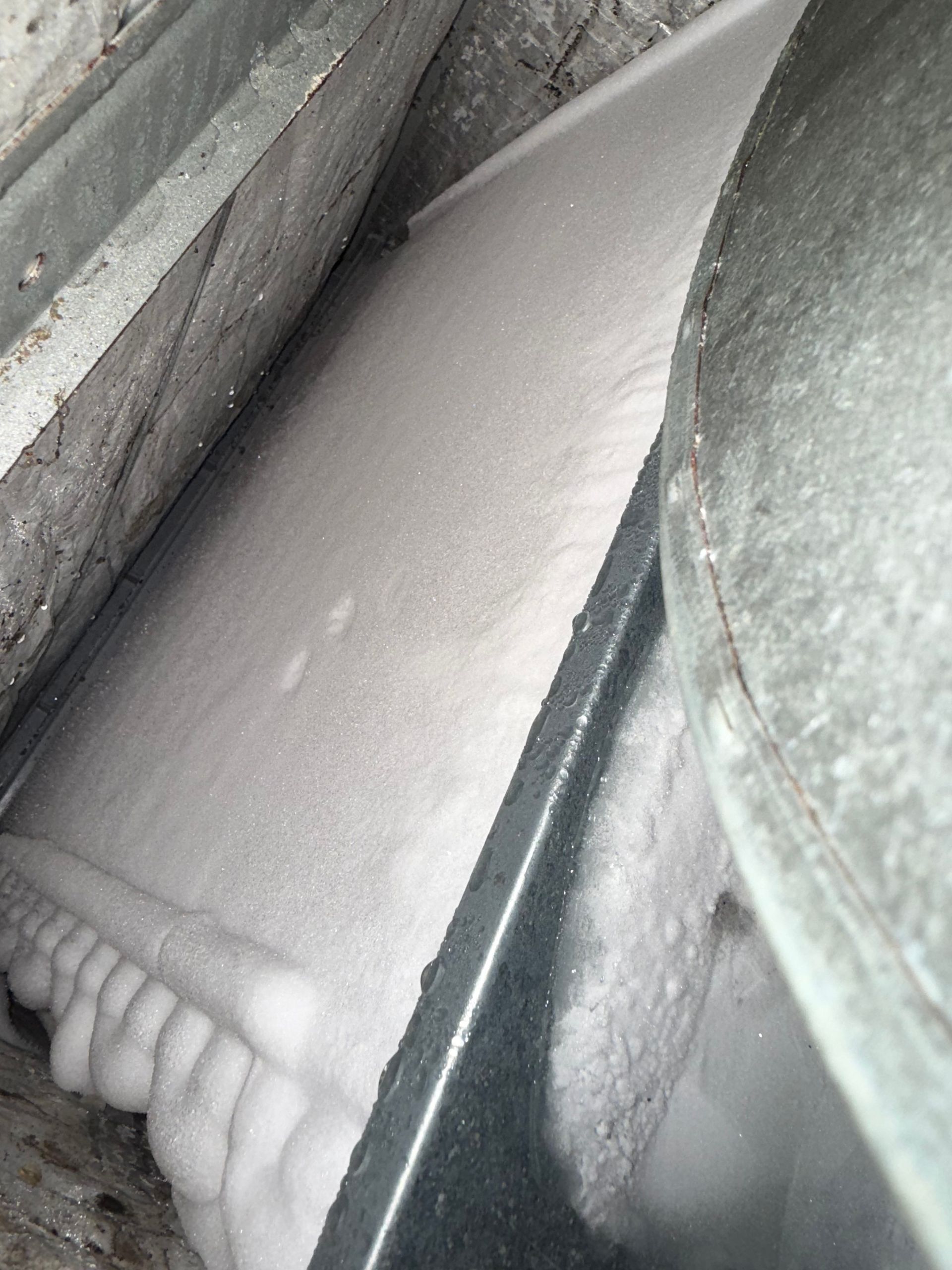 An air conditioning evaporator coil covered in a thick layer of white ice, indicating a cooling system malfunction.