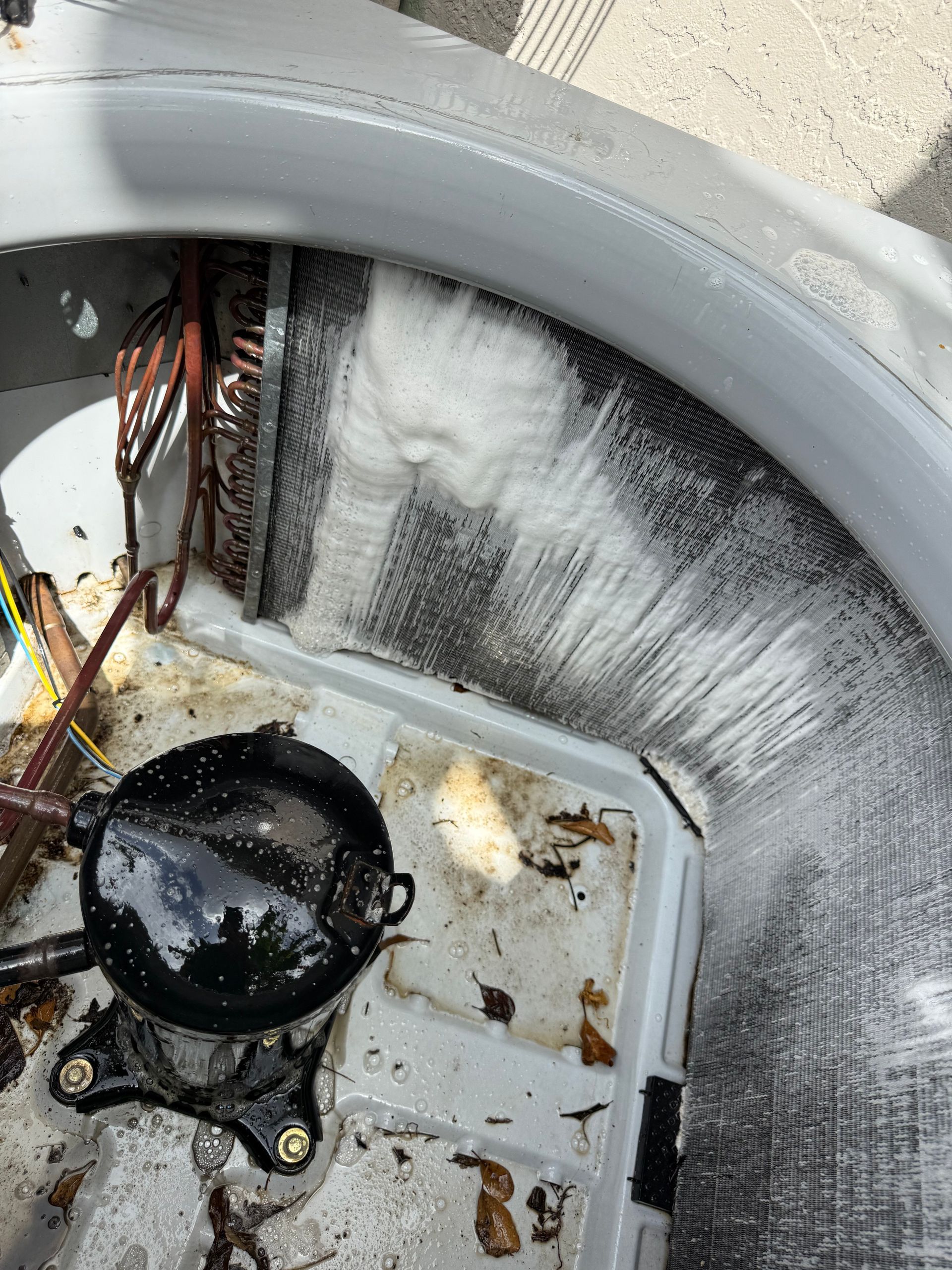 Inside of an outdoor AC unit showing a black compressor and frosted, icy refrigerant coils.