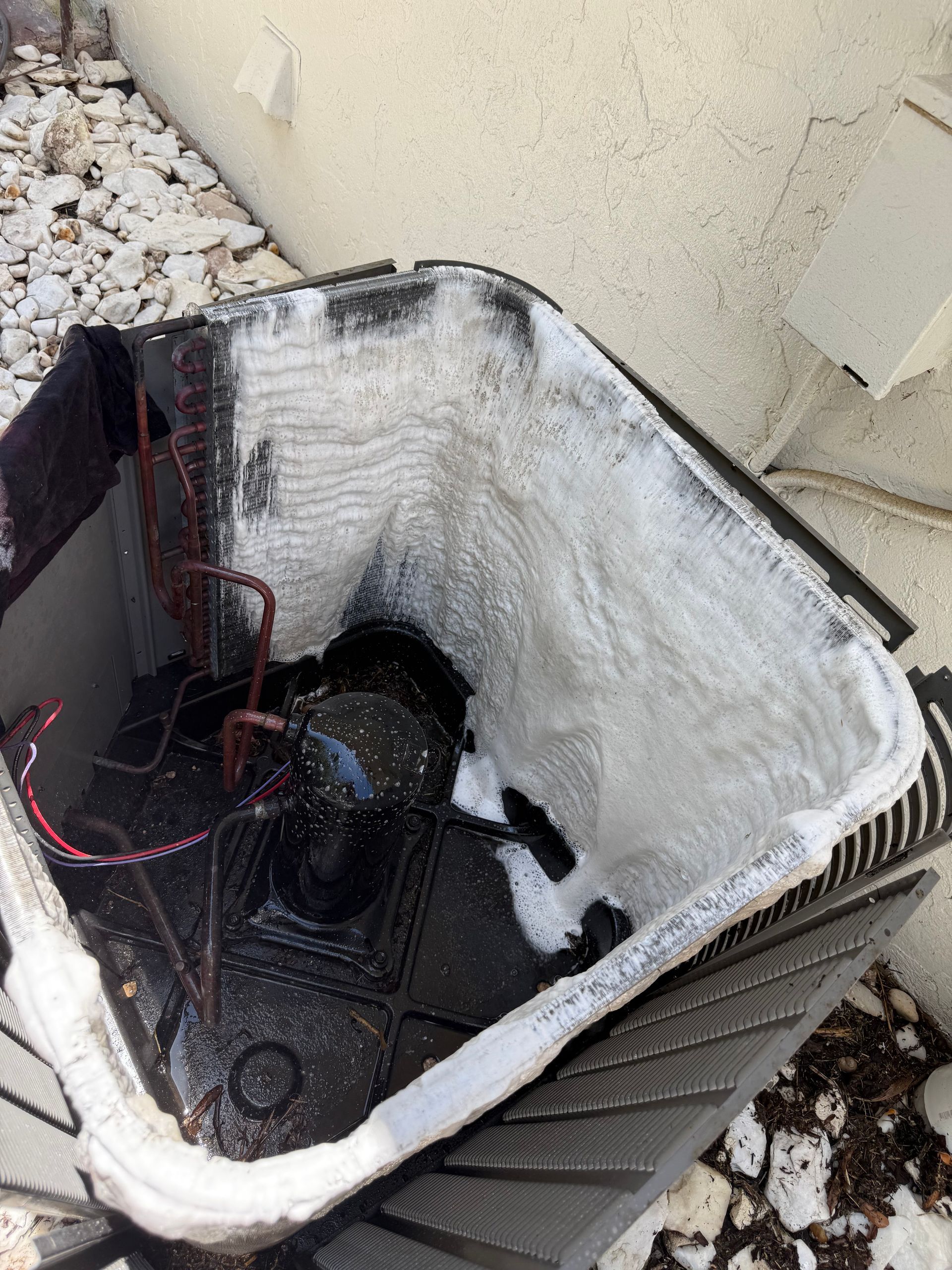 Outdoor air conditioning unit with the top cover removed, revealing internal cooling coils heavily frosted with ice.