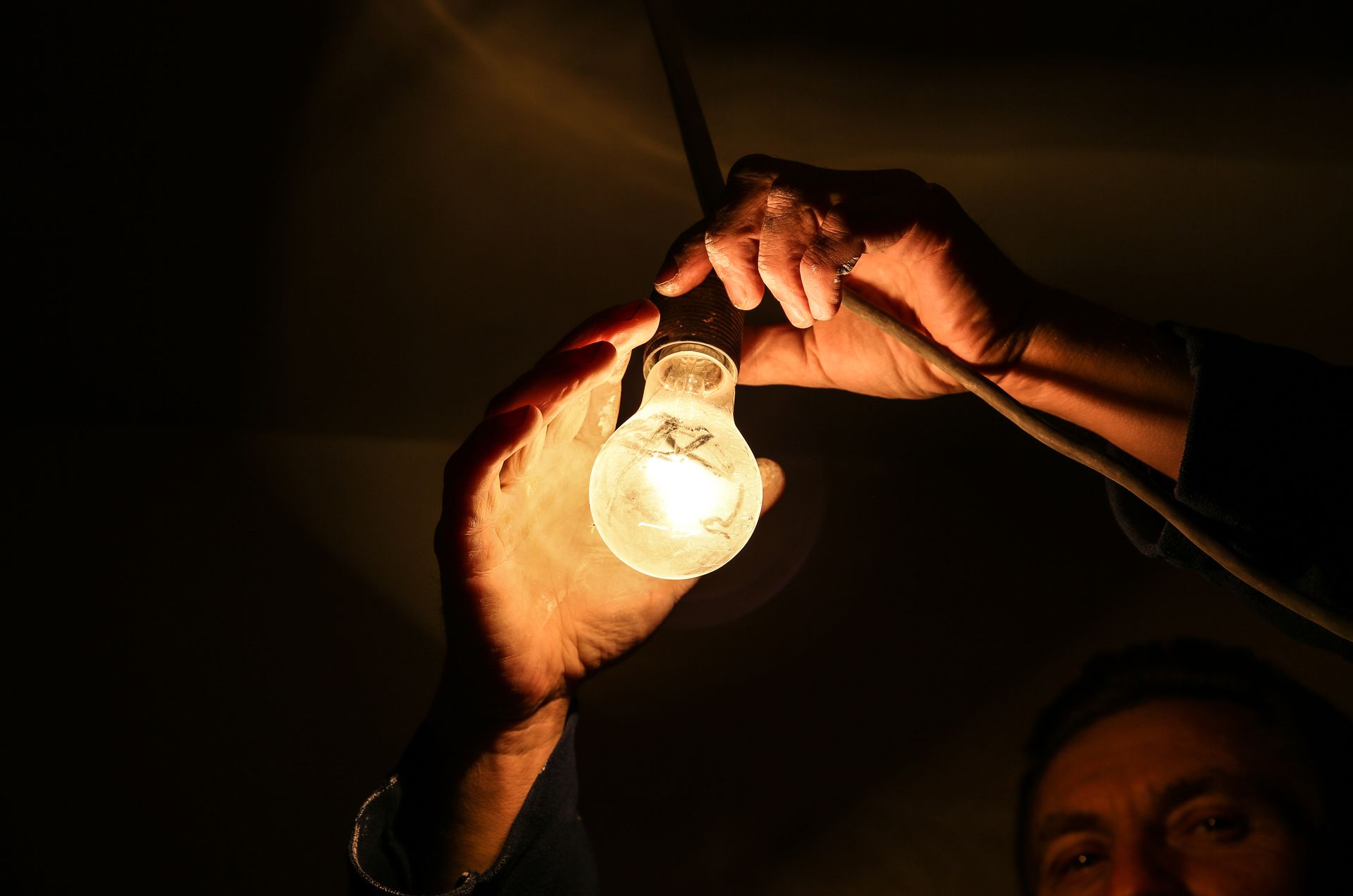 a man is holding a light bulb in his hands in the dark .