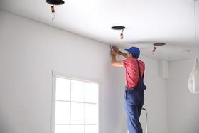 a man is installing a ceiling in a room .