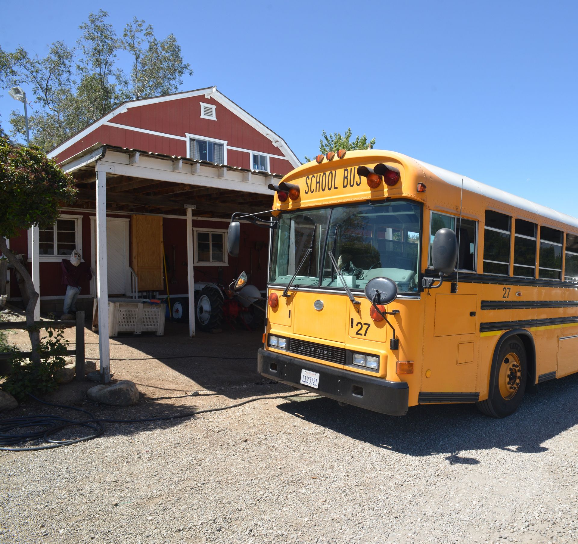 A yellow school bus is parked in front of a barn