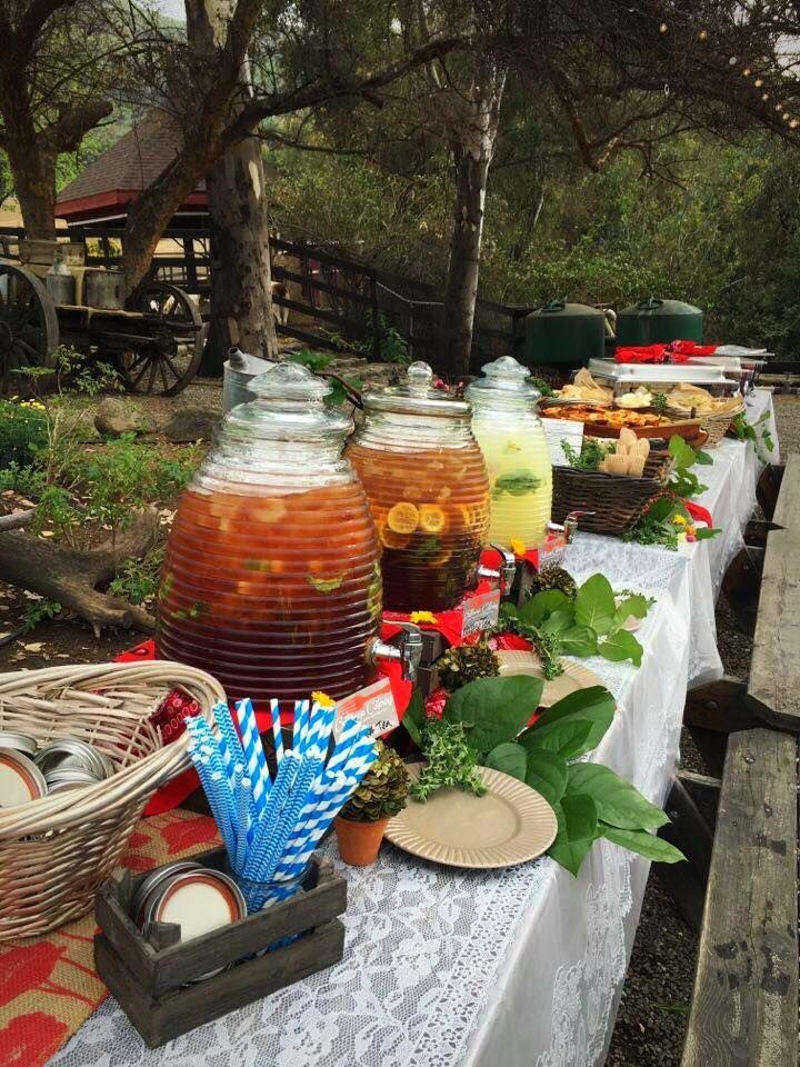 A long table with a variety of drinks and food on it.