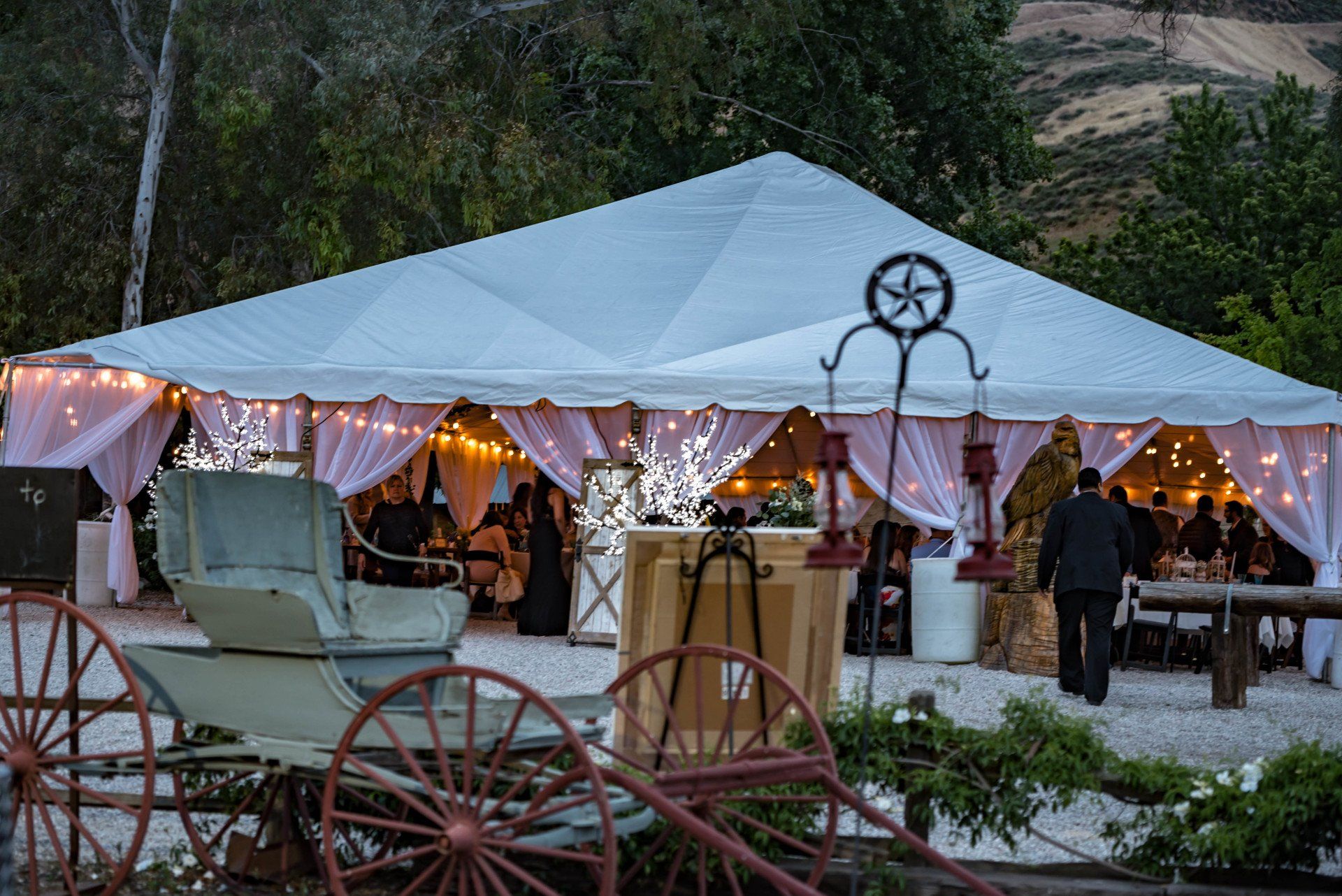 A white tent with a horse drawn carriage in front of it.