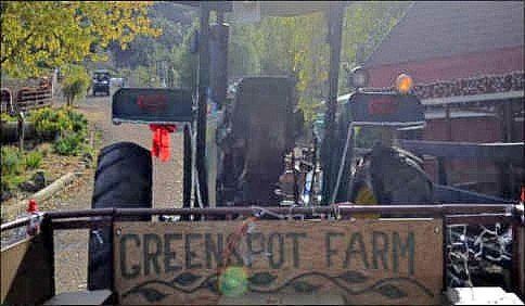 A tractor is driving down a road next to a sign that says Greenspot farm.