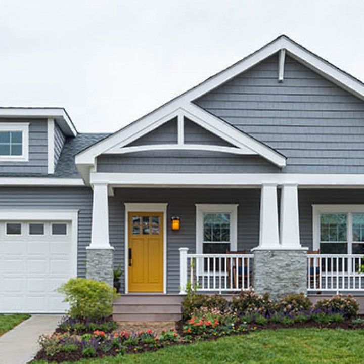 Person in a white shirt and gloves, using a long trowel to apply drywall mud to a wall and ceiling.