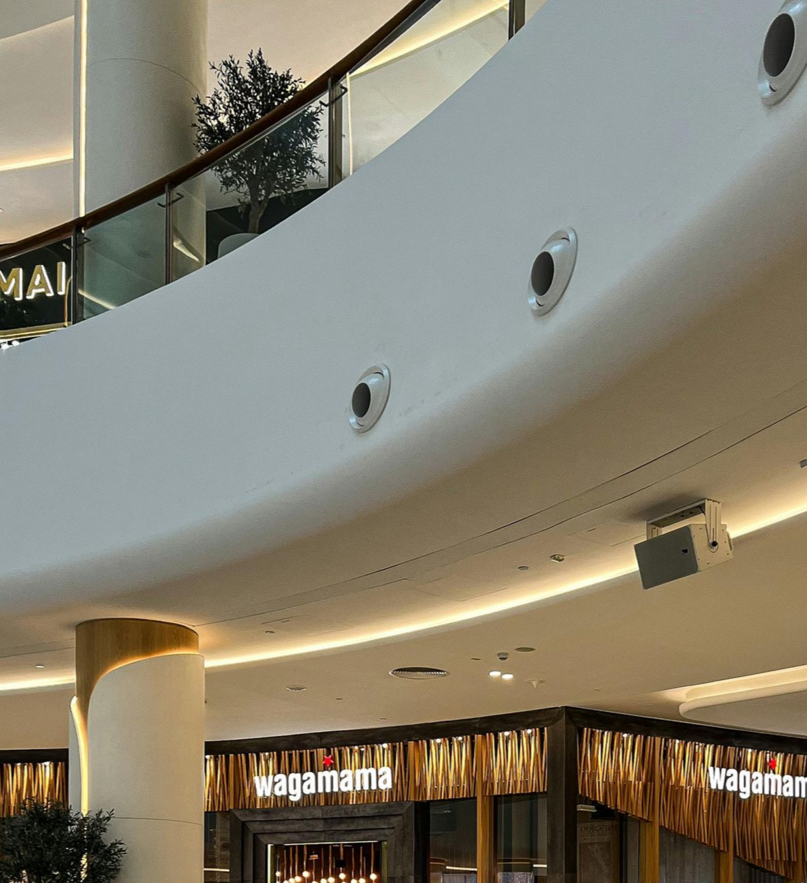 Mall interior with a Wagamama restaurant, curved ceiling with vents, and a glass railing.