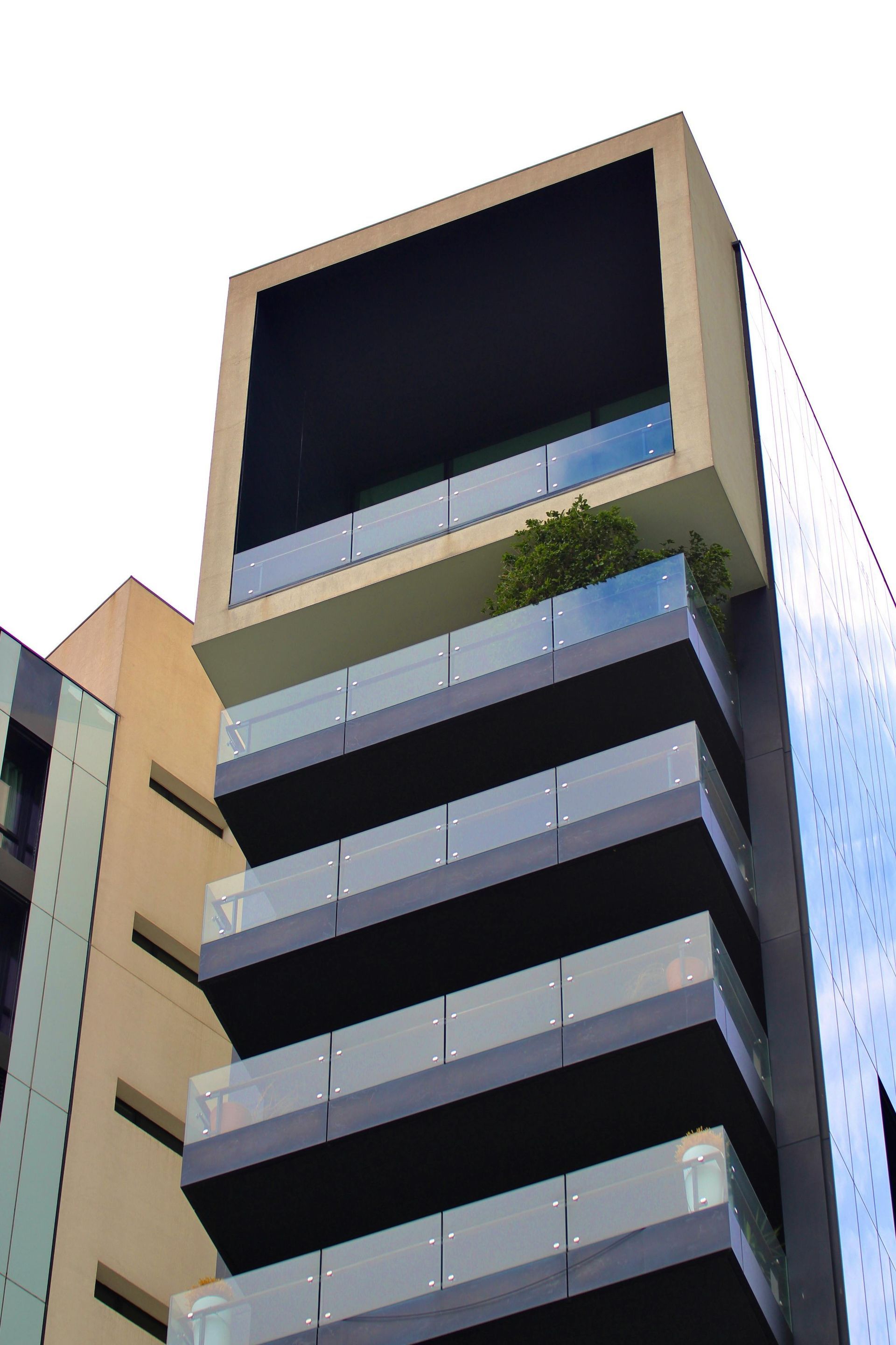 Modern building with stacked balconies and a large, square top section.