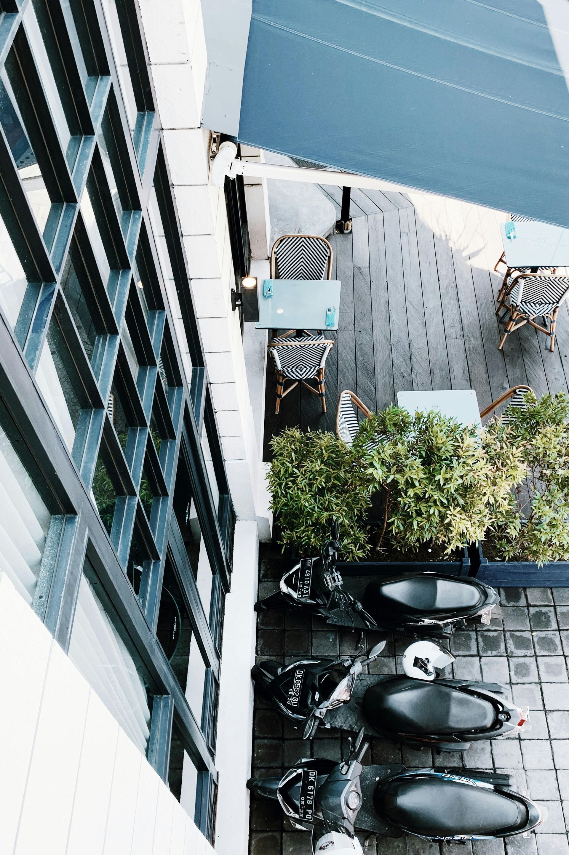 Overhead view of outdoor seating area with tables, chairs, and shade canopy. Black and white checkered and aqua.