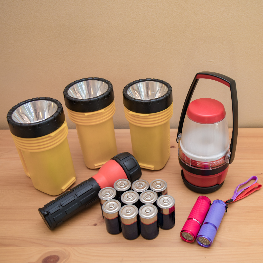 A bunch of flashlights and batteries on a wooden table