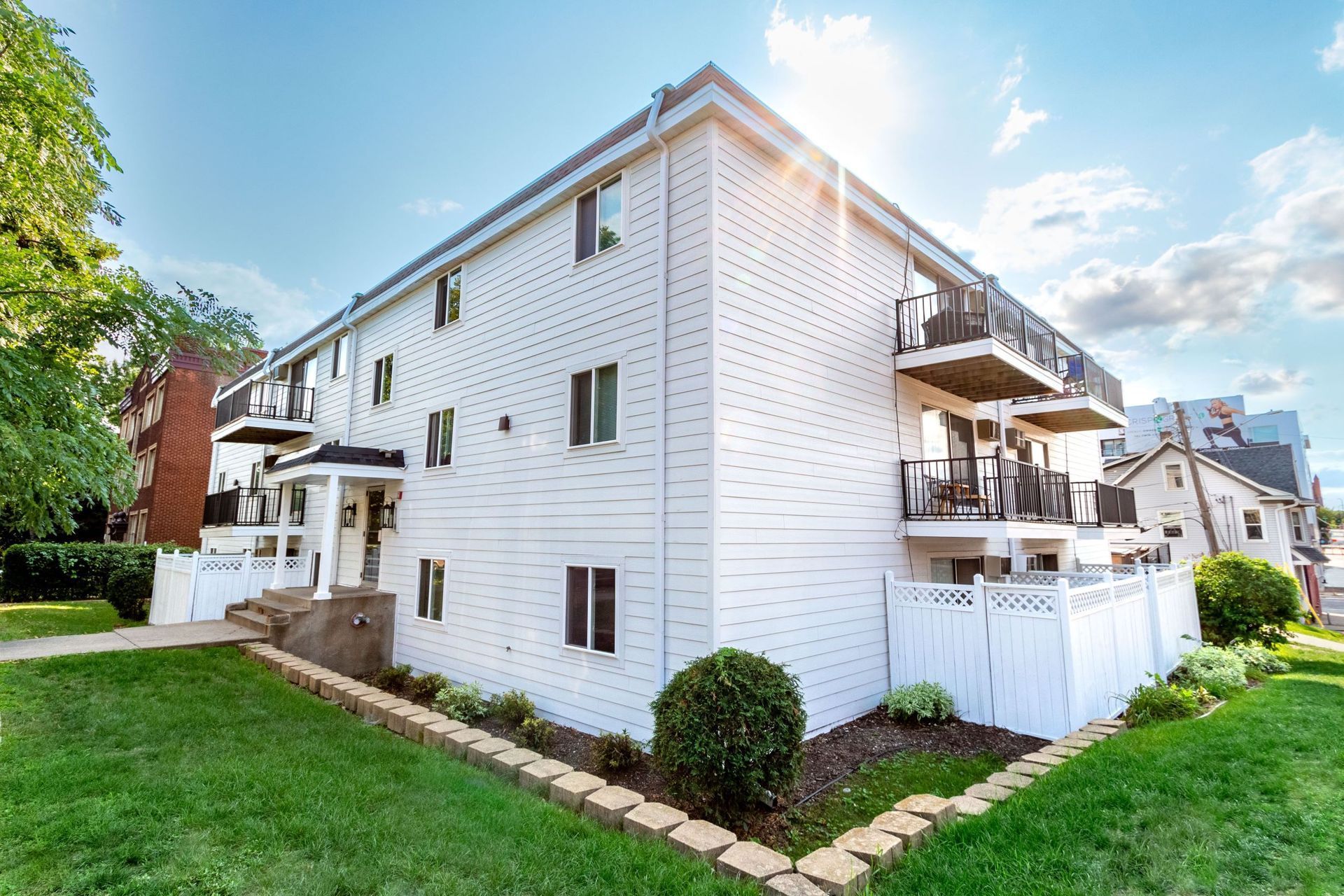 A large white apartment building with a lush green lawn in front of it.