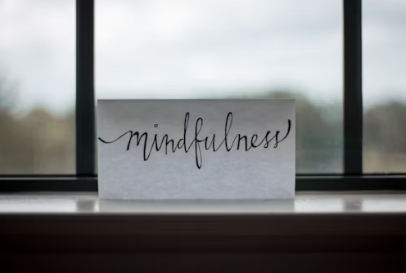 A piece of paper with the word mindfulness written on it is sitting on a window sill.