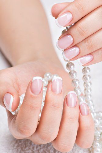 Hands with short manicured nails holding pearls