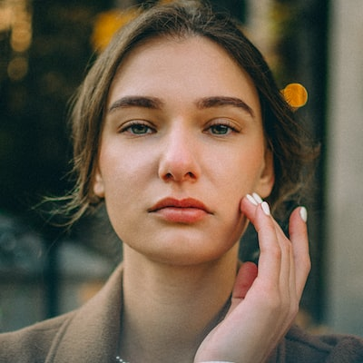 Een close-up van het gezicht van een vrouw met haar hand op haar kin.