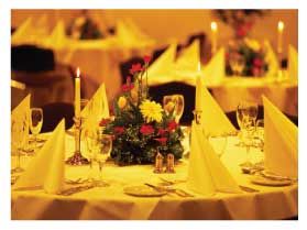 A table set for a dinner party with yellow napkins and candles.