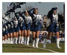 A group of cheerleaders are marching on a field.