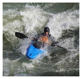 A man is paddling a blue kayak down a river.