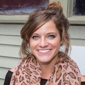 A woman wearing a leopard print scarf is smiling for the camera