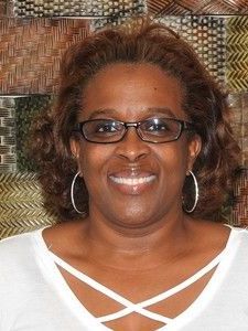 A woman wearing glasses and hoop earrings is smiling for the camera.