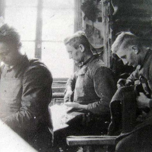 Ein Schwarzweißfoto von drei Männern, die in einer Fabrik arbeiten
