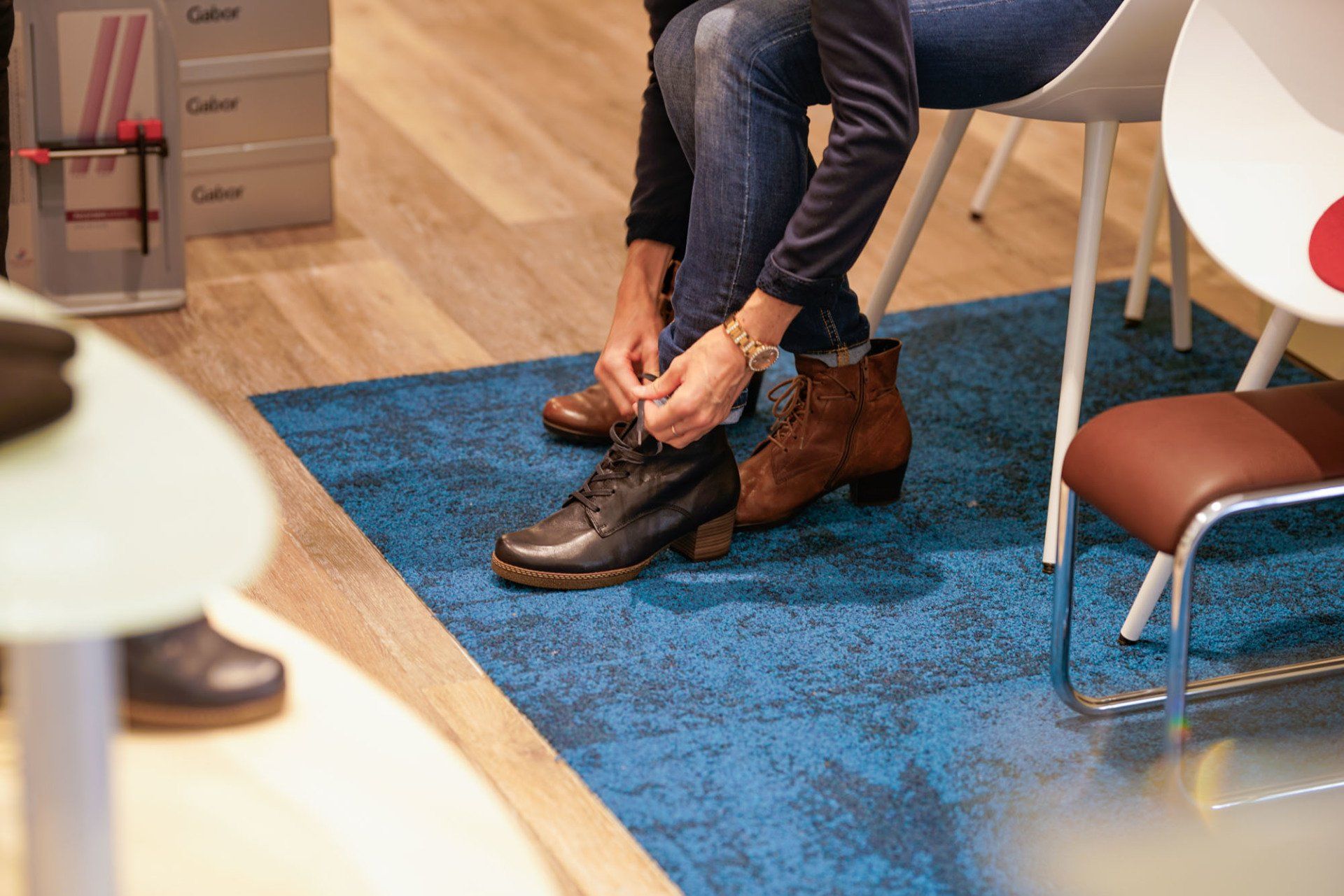 Eine Person bindet in einem Schuhgeschäft ihre Schuhe.