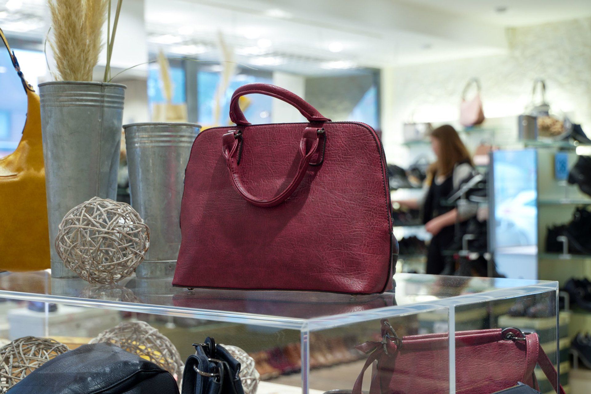 Eine rote Handtasche liegt auf einem durchsichtigen Regal in einem Geschäft.
