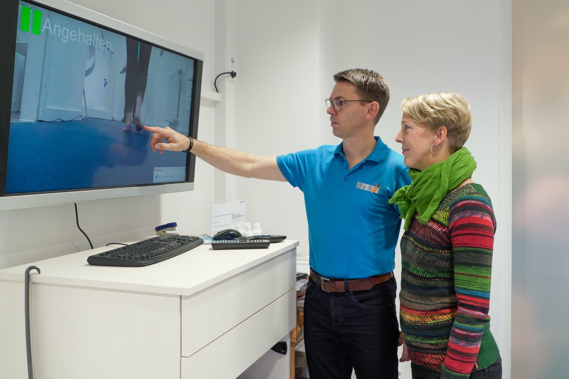 Fachberater zeigt Kundin eine Videoanalyse ihrer Gangbewegung am Bildschirm