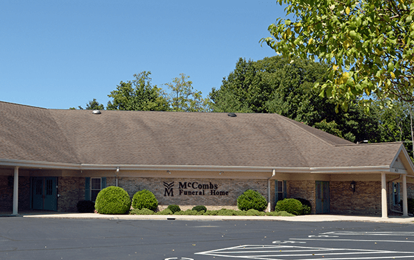 A large brick building is surrounded by tall grass and trees.