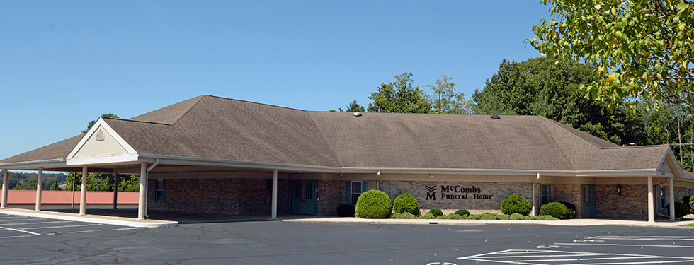 A large brick building with a brown roof and a parking lot in front of it