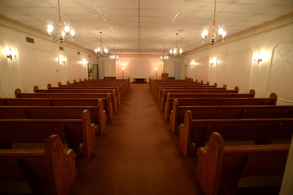 There are rows of wooden benches in an empty church.
