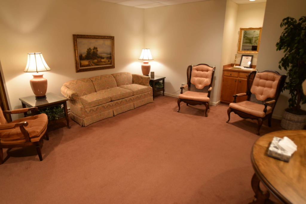 A living room with a couch , chairs , lamps and a table