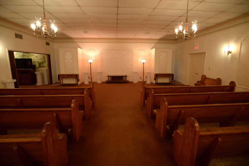 An empty church with wooden benches and a chandelier.