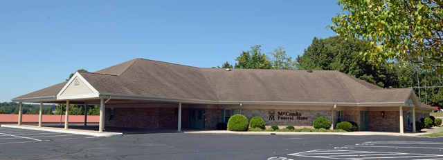 A large brick building with a canopy and a parking lot in front of it.