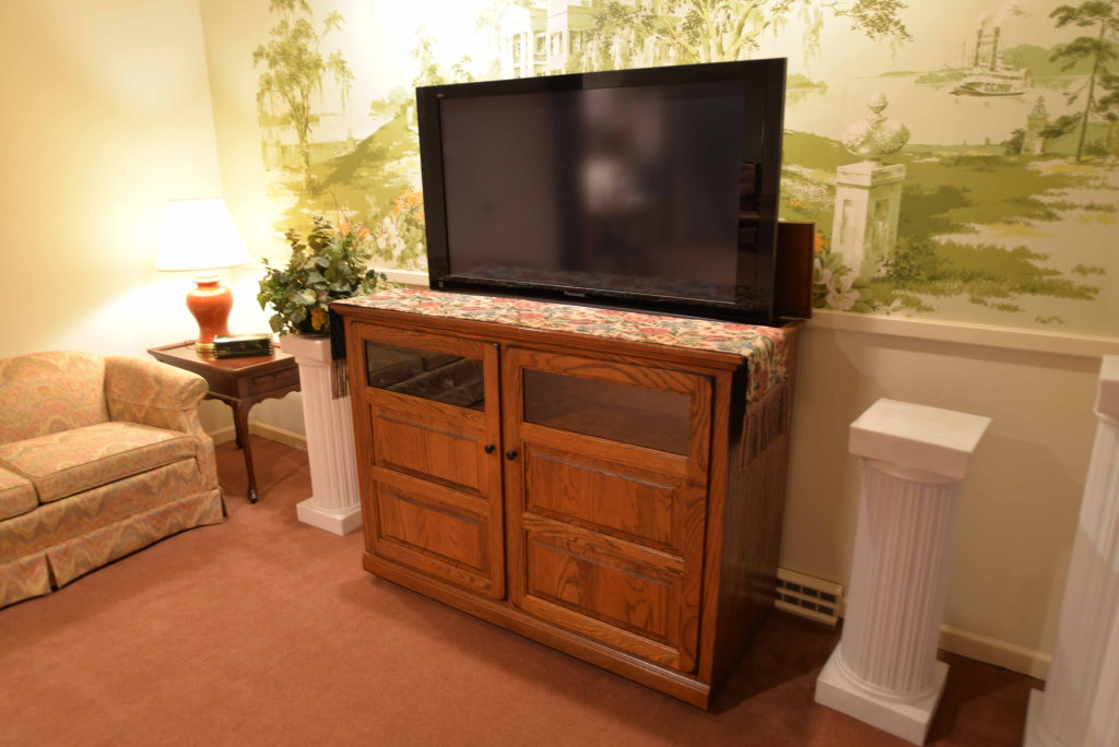 A living room with a flat screen tv on a wooden entertainment center.