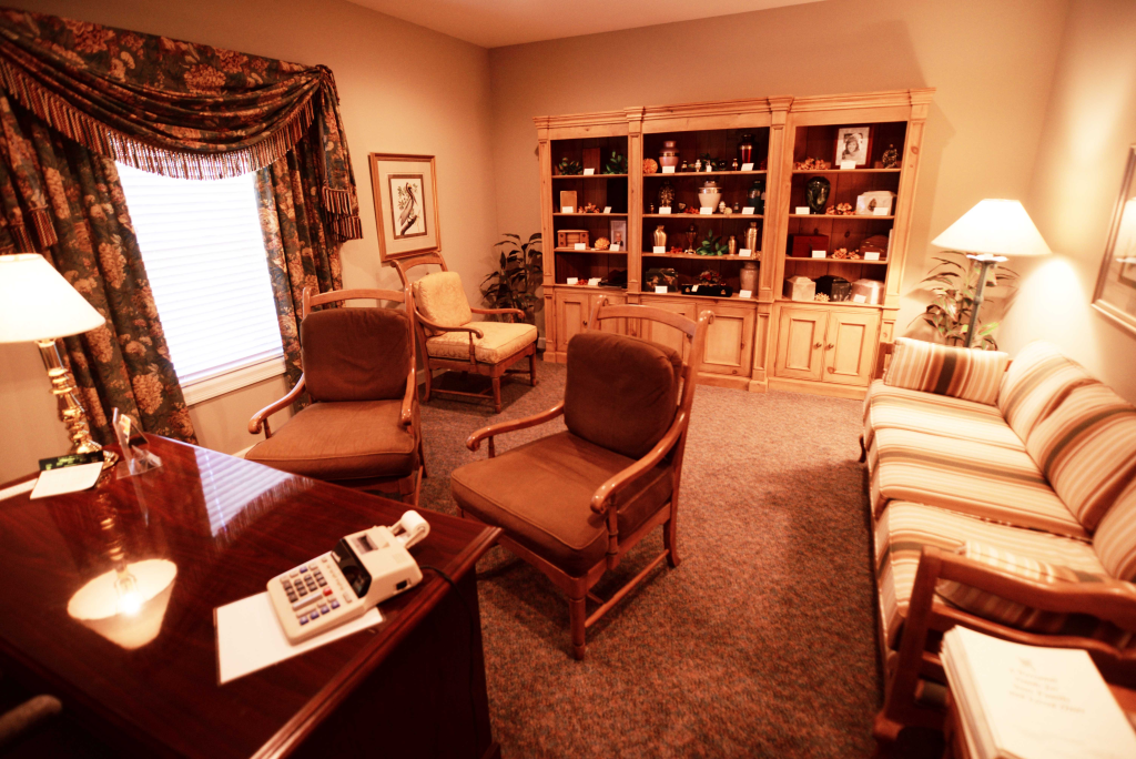 A living room with a couch and chairs and a desk with a calculator on it