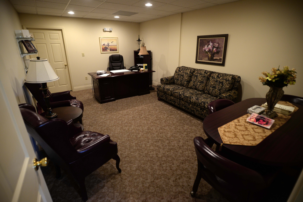 A living room with a couch , table , chairs and a desk.