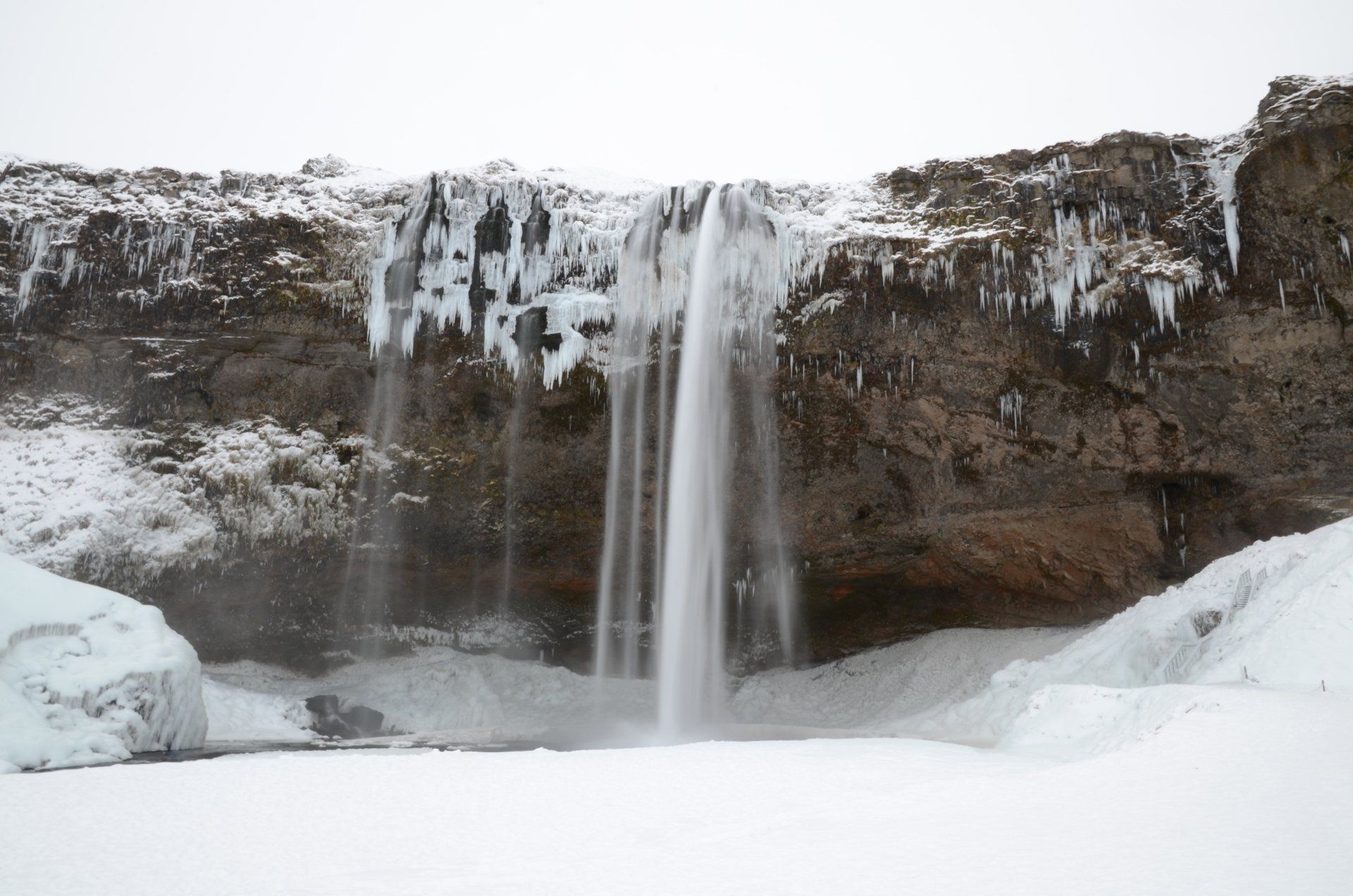 雪に覆われても美しい白糸を流すアイスランドの滝