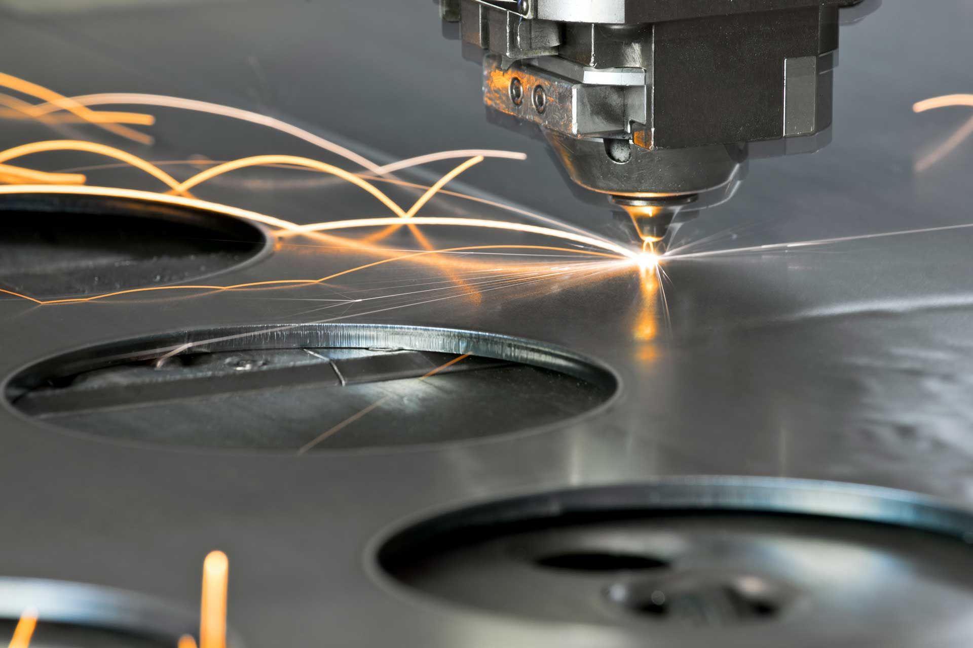 A machine is cutting a piece of metal with sparks coming out of it.