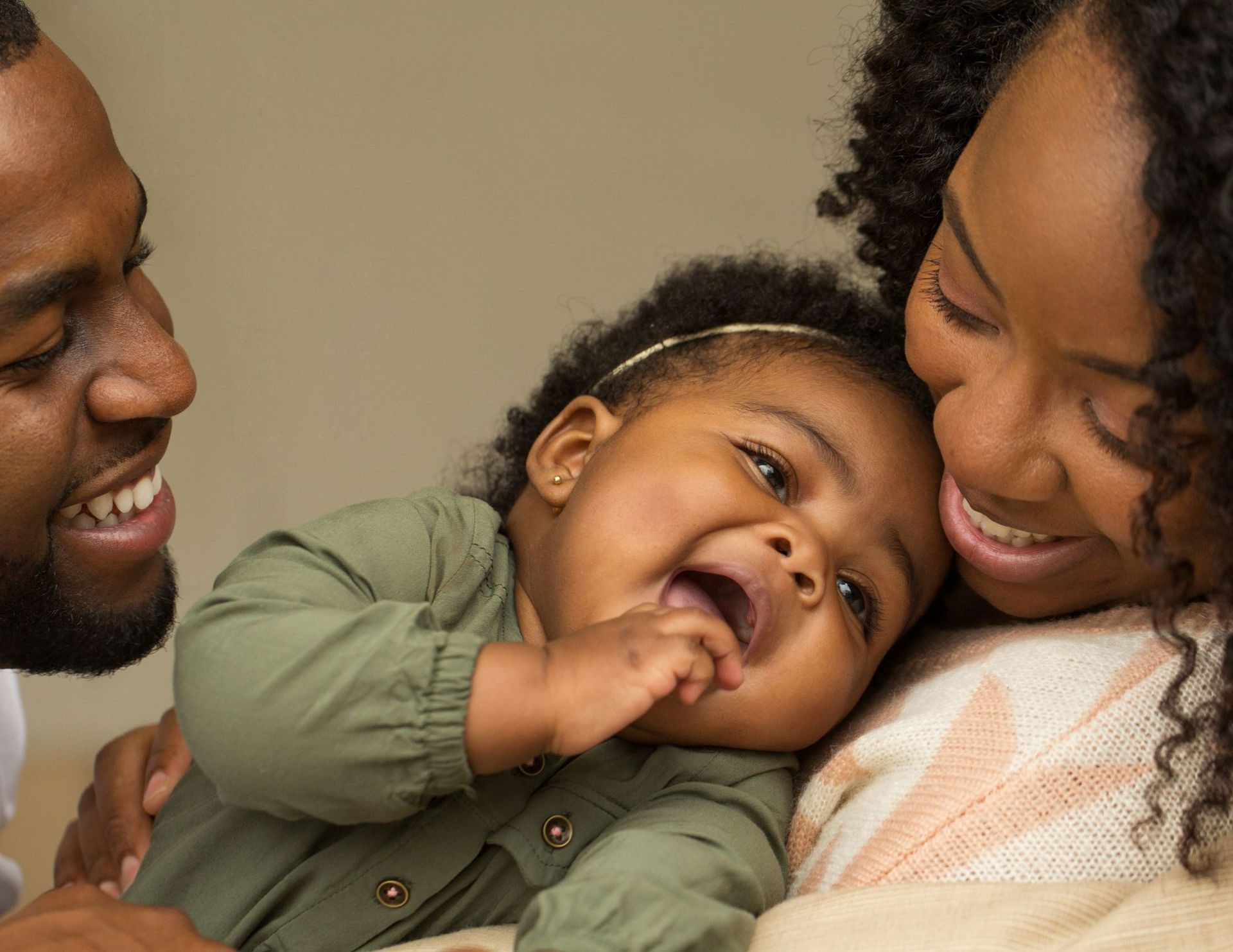 A man and woman are carrying a little girl on their shoulders.