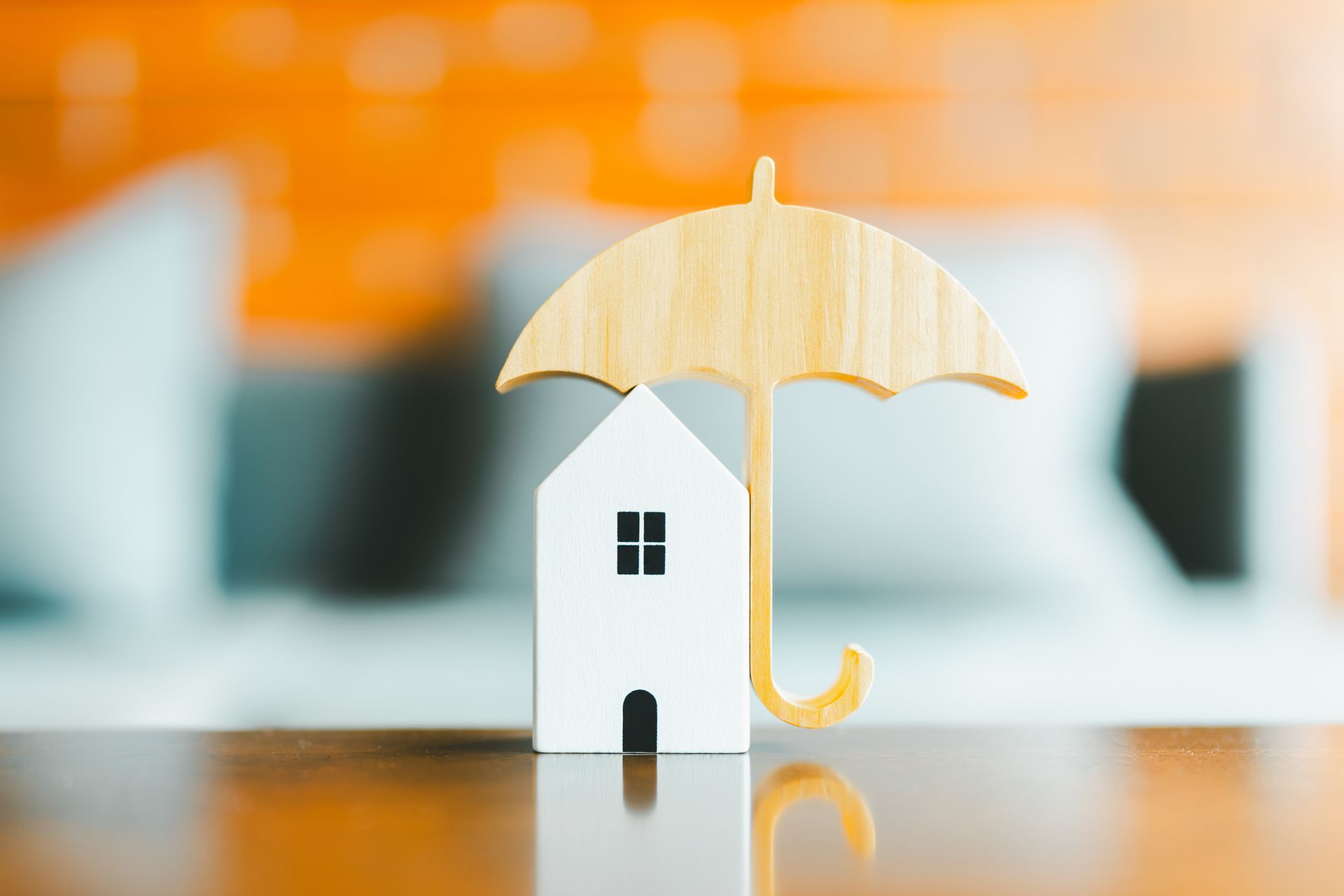 Model of umbrella with house on wooden table.