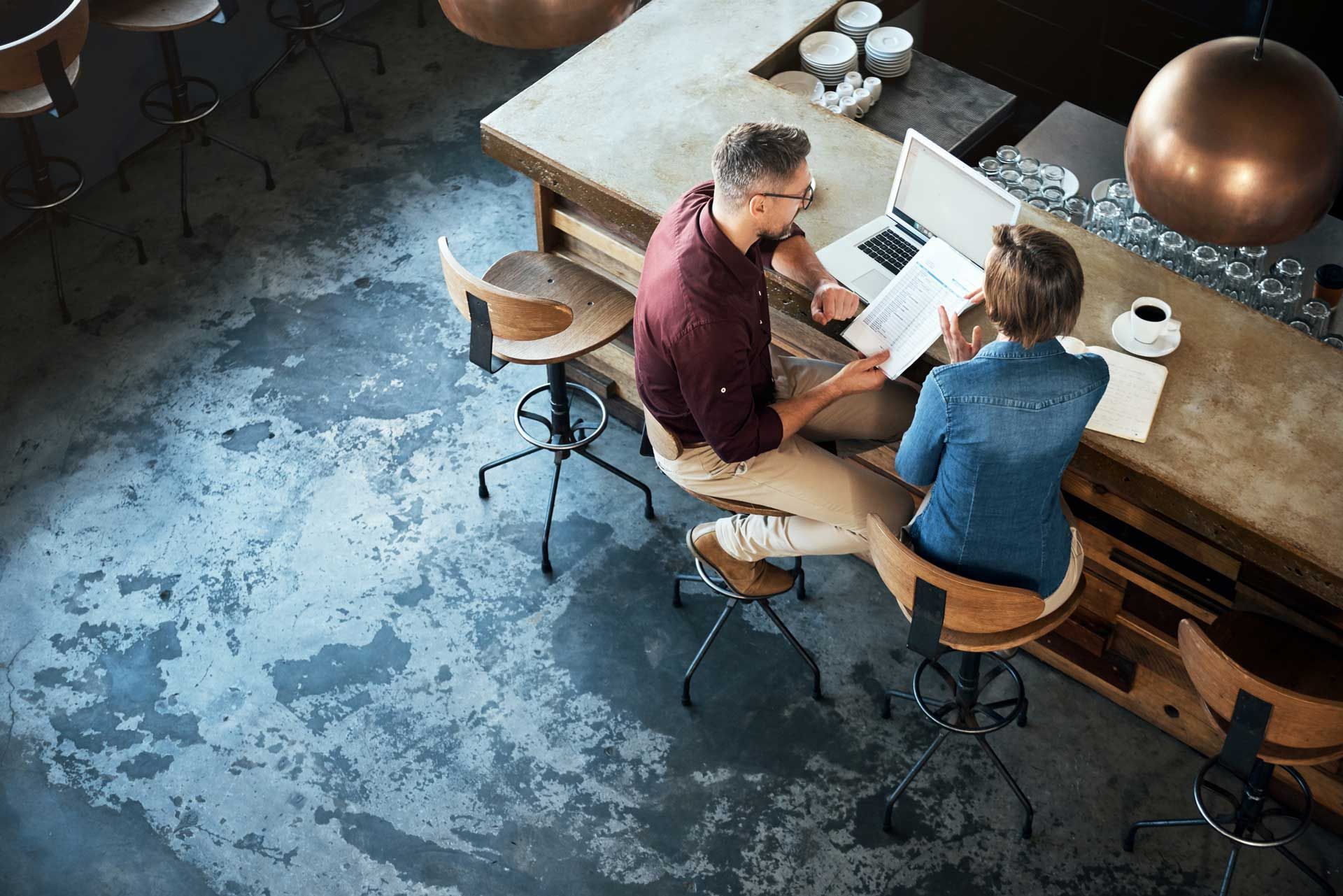 A man and a woman are sitting at a table with a laptop.