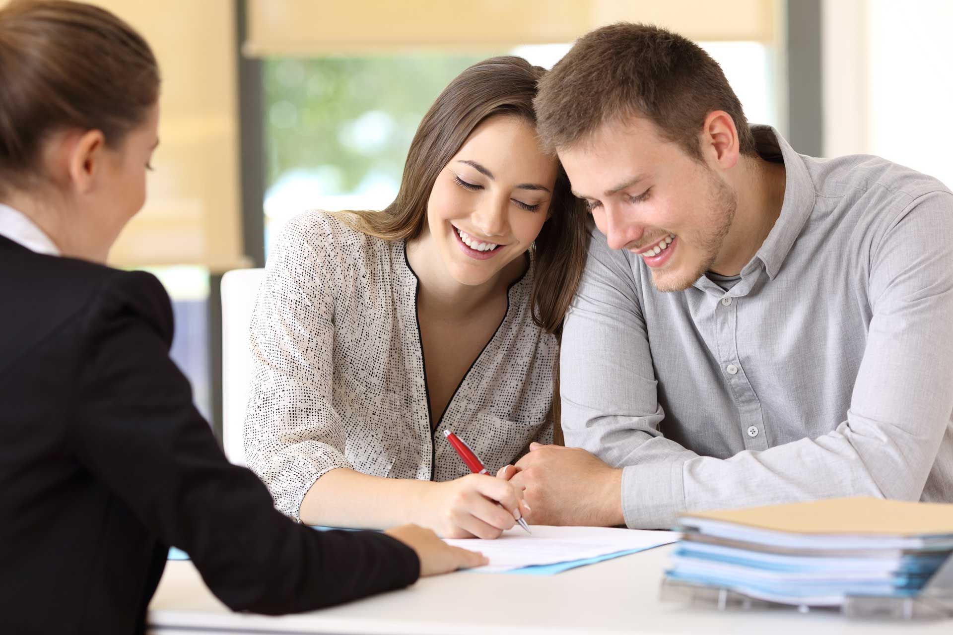 A man and a woman are sitting at a table signing a document.