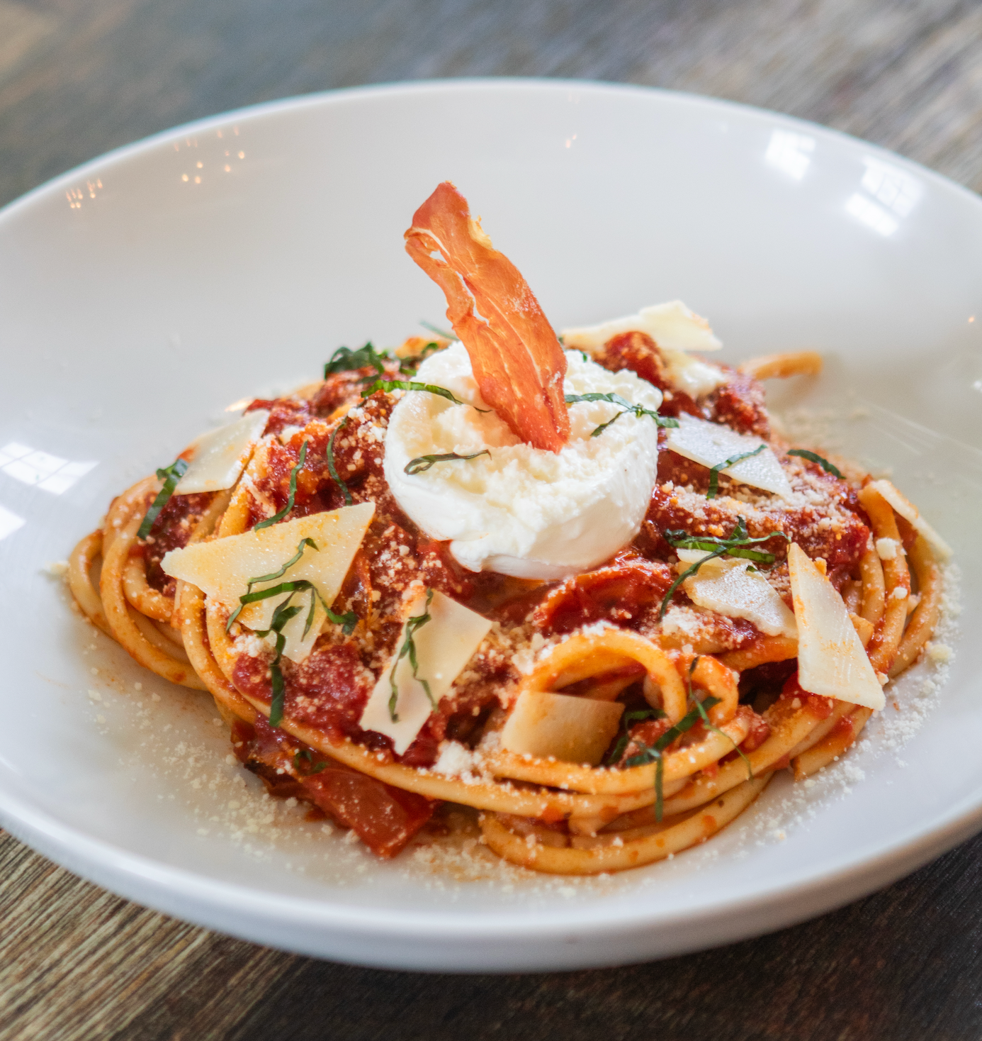 A wooden table topped with plates of food and a bottle of wine.