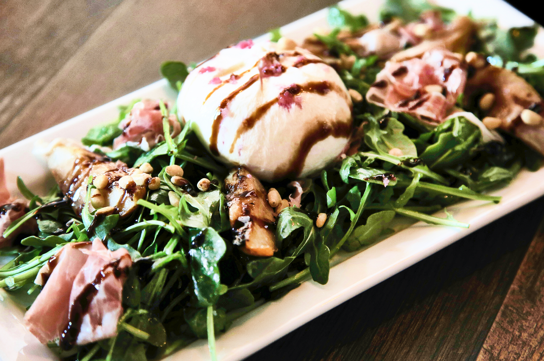 A steak is cooking in a frying pan on a wooden cutting board.
